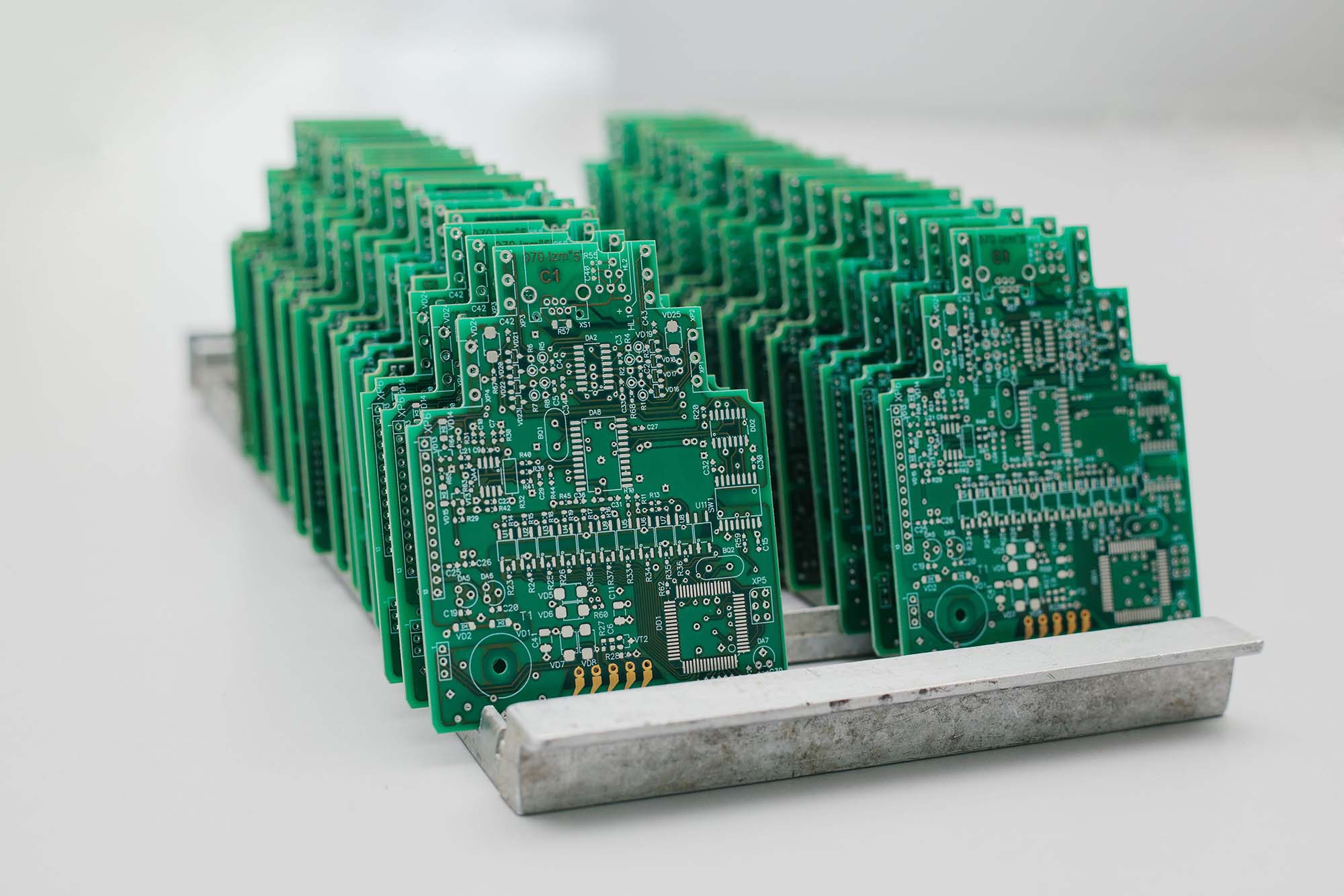 Rows of finished green PCBs racked in production, representing the volume and repeatability High Mix electronics manufacturing depends on
